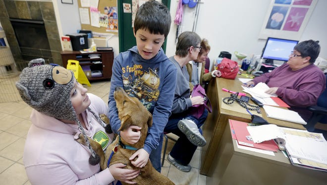 Amber Harrell, left, and her son, Donovan Heckner, play with Lady, while volunteer Kathy Paevk, right, helps Nancy Heckner and Michelle McGinnis fill out adoption papers at Chances Animal Rescue in Appleton on Wednesday. Nancy Heckner is adopting the lab mix. The center is scrambling to find homes for more than 100 cats and dogs before being evicted.