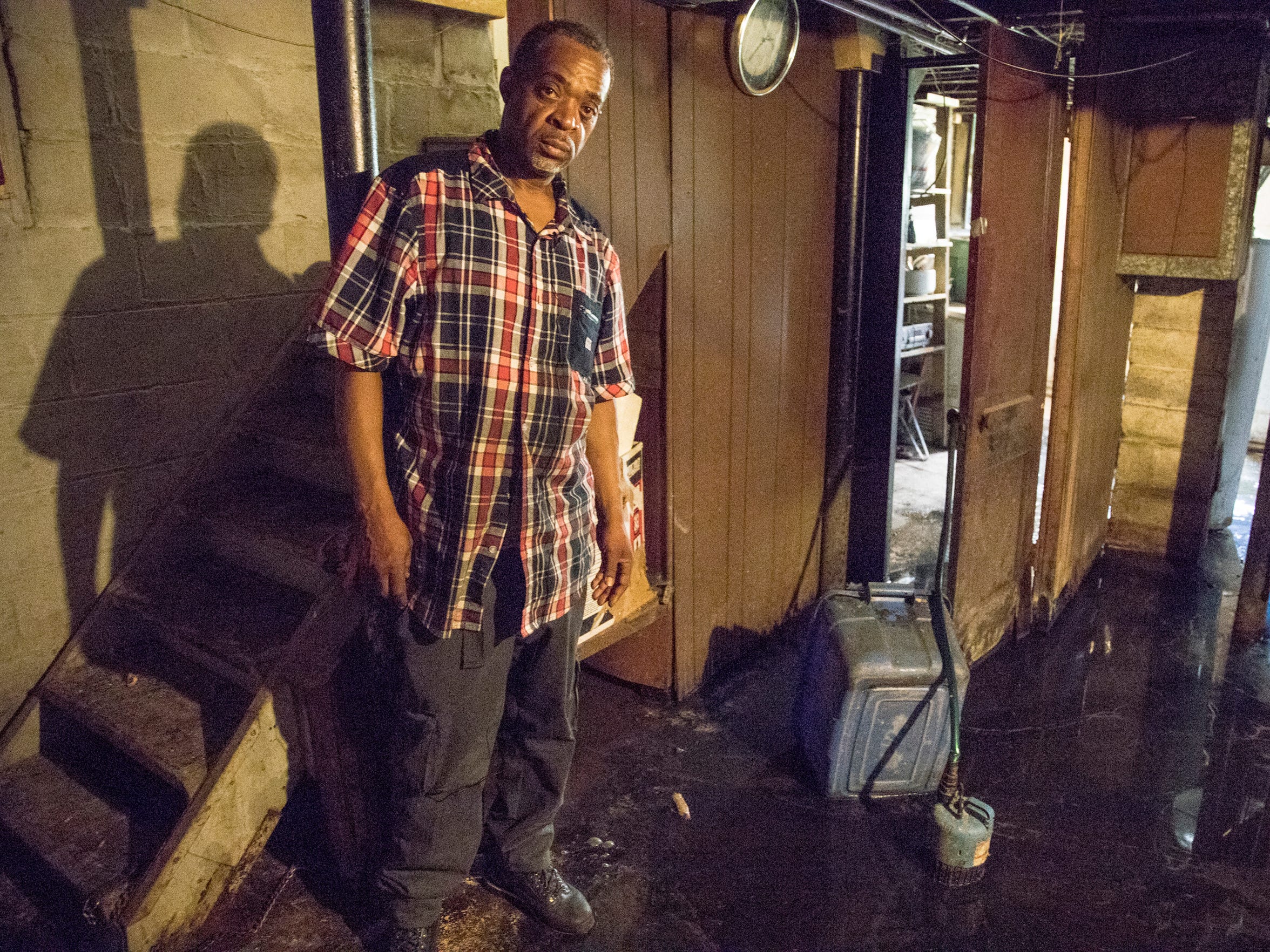 William Love poses in May for a photo in the flooded basement of the house on Hull Street in Detroit that he is purchasing from the land bank. (Photo taken May 31, 2018)