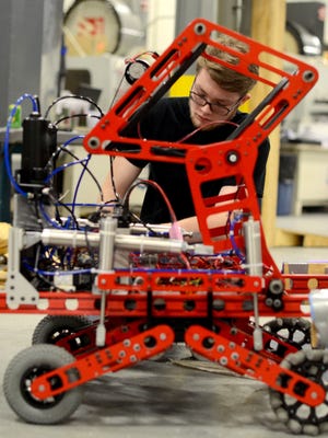 Joseph George tends to his team's robot Sunday, Feb. 21, during testing of their robot at PTM corporation in Fair Haven.