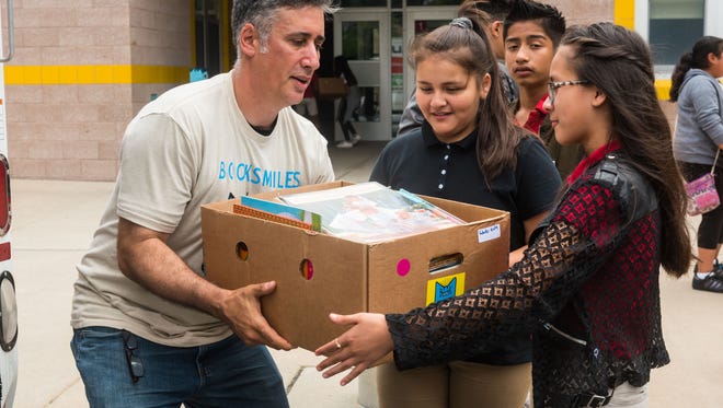 Larry Abrams of Book Smiles unloads boxes with the help of Stephanie Canseco and Kimberli Chavez at Sabater Elementary School on Tuesday, June 19.