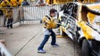 A young fan takes a swing at the smash car before game