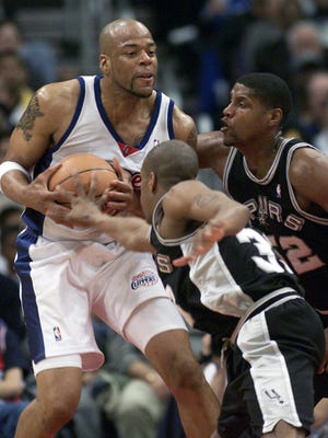 In this Saturday, April 7, 2001 file photo, Los Angeles Clippers' Sean Rooks fends off San Antonio Spurs defenders Antonio Daniels and Samaki Walker, right, during a game. Former NBA center and Philadelphia 76ers assistant coach Sean Rooks has died. He was 46. (AP Photo/Jill Connelly, File)