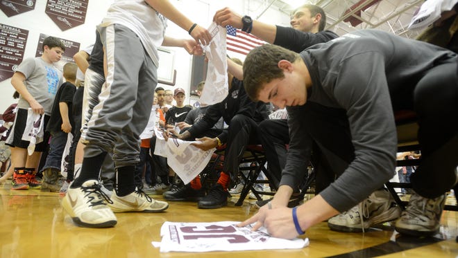 John Glenn High School boys basketball team players sign autographs during a pep rally on Tuesday.