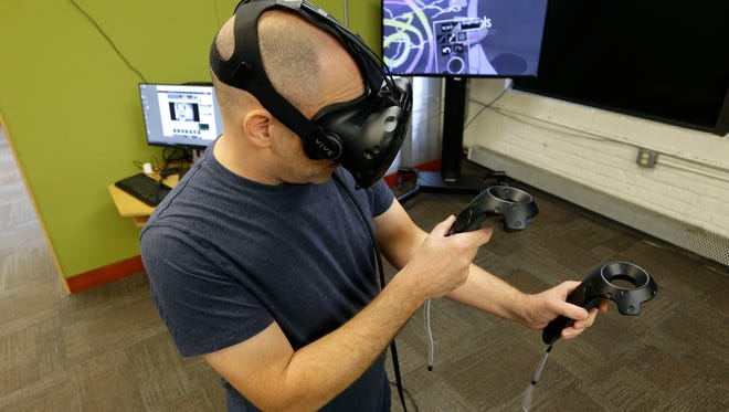 Ben Dembroski, the Maker space/openlab manager at Milwaukee Institute of Art and Design, demonstrates a virtual reality headset at the school on E. Erie St., in Milwaukee on Thursday, October 6, 2016. Dembroski is teaching students how to create art using virtual reality headset and a 3D printer this semester.