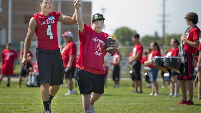 Jon Miller and Cole DiNardo hold up their hands as they are introduced during Victory Day Saturday, August 15, 2015 in Memorial Stadium at Port Huron High School. The event paired special needs students with mentors from the football and cheerleading teams.