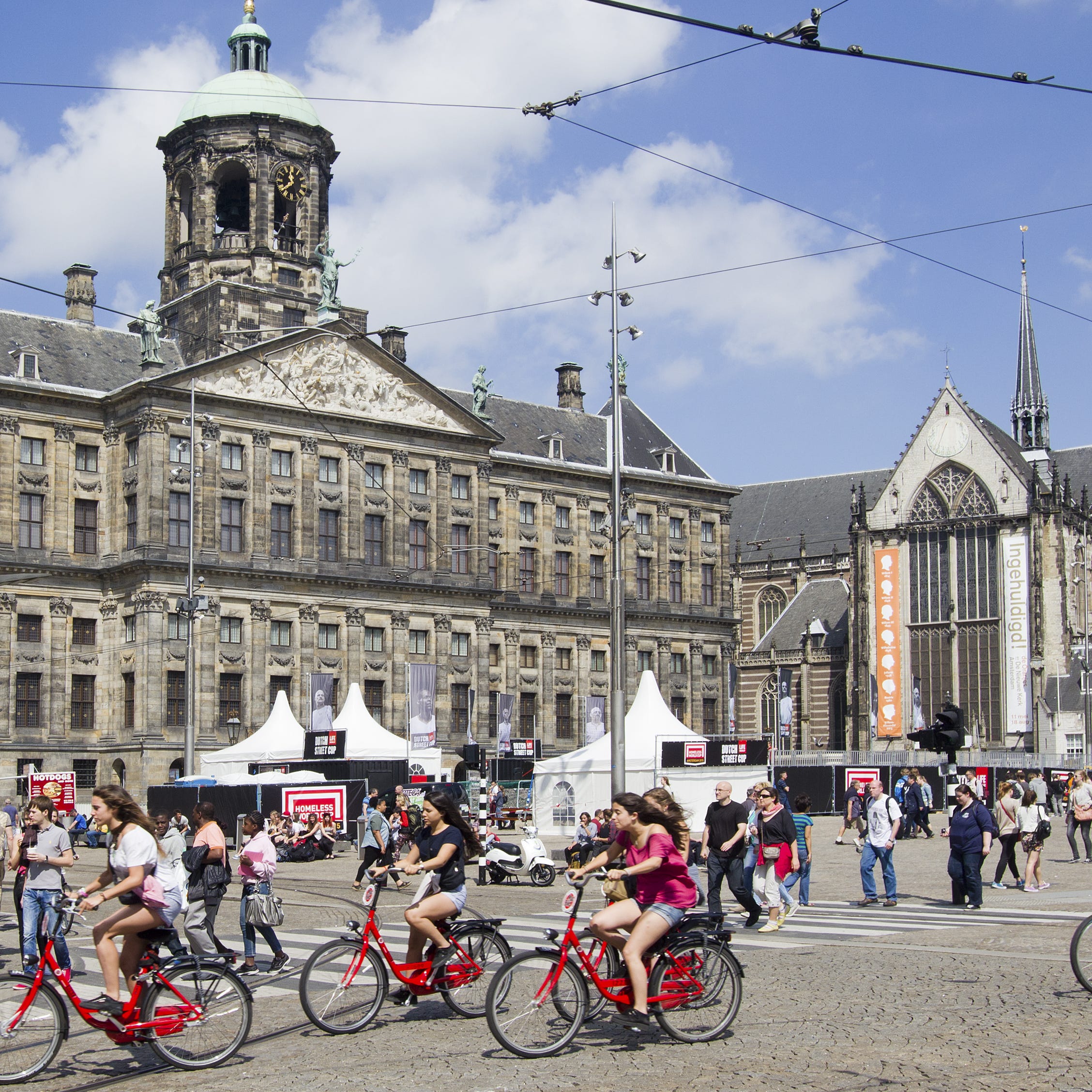 Tourists bike through Amsterdam's Dam Square.