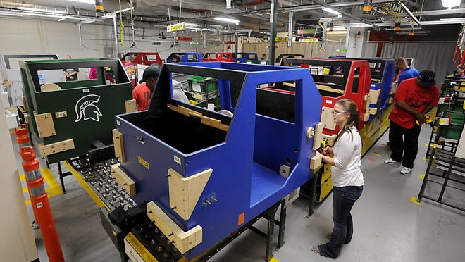 Newly-hired GM Lansing Grand River plant employees train for specific tasks as wooden cars roll down the line in simulated work environment training on Wednesday . GM is adding a second shift at the plant and the new workers will be helping Cadillacs and Camaros.