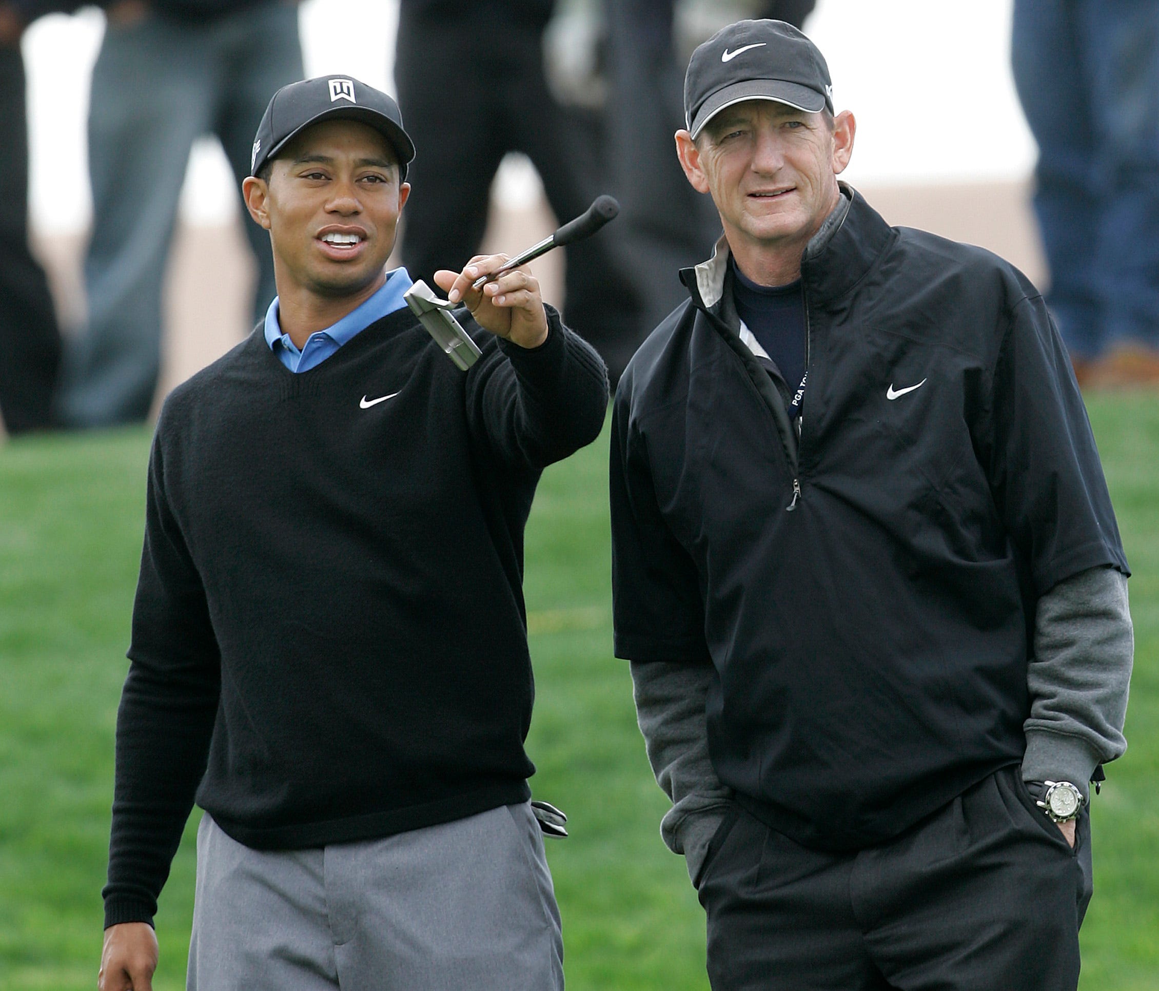 Tiger Woods uses his putter to indicate a point of interest to ex-coach Hank Haney during a practice session for the World Golf Championships in 2007.