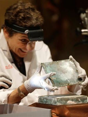 Museum of Fine Arts Boston Head of Objects Conservation Pam Hatchfield removes a metal lid from a time capsule at the museum, Tuesday, Jan. 6, 2015, in Boston. The original capsule was made of cowhide and believed to have been embedded in a cornerstone when construction on the state Capitol building began in 1795. The contents were shifted to a metal box in 1855 which was unearthed last month at the Statehouse. (AP Photo/Steven Senne)