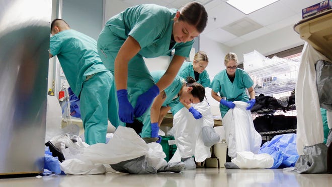Members of the Department of Defense's Ebola Military Medical Support Team dress with protective gear during training at San Antonio Military Medical Center in San Antonio.