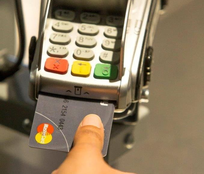 A person uses a thumbprint to make a purchase with a credit card that uses biometric technology to authenticate the cardholder.