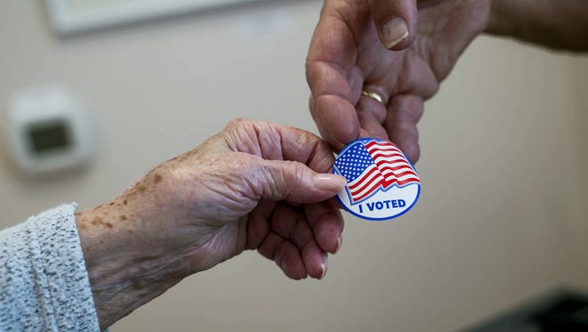 A poll worker hands a voter an "I voted" sticker on May 20, 2014.