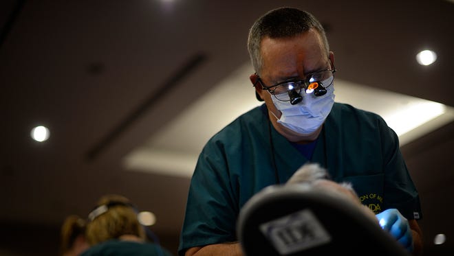 Dr. Bob Snyder of Green Bay works on a patient during the Wisconsin Dental Association's Mission of Mercy. The June event, staffed by volunteers, provided partials, fixed and cleaned teeth and performed other dental work.