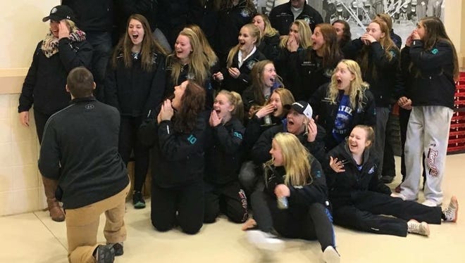 Sartell/Sauk Rapids girls hockey assistant coach Alex Nelson receives a surprise proposal from her boyfriend Brian Kampa during a team photo following a game at Jan. 23 in Thief River Falls.
