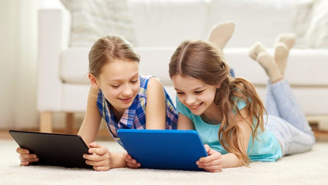people, children, technology, friends and friendship concept - happy little girls with tablet pc computers lying on floor at home