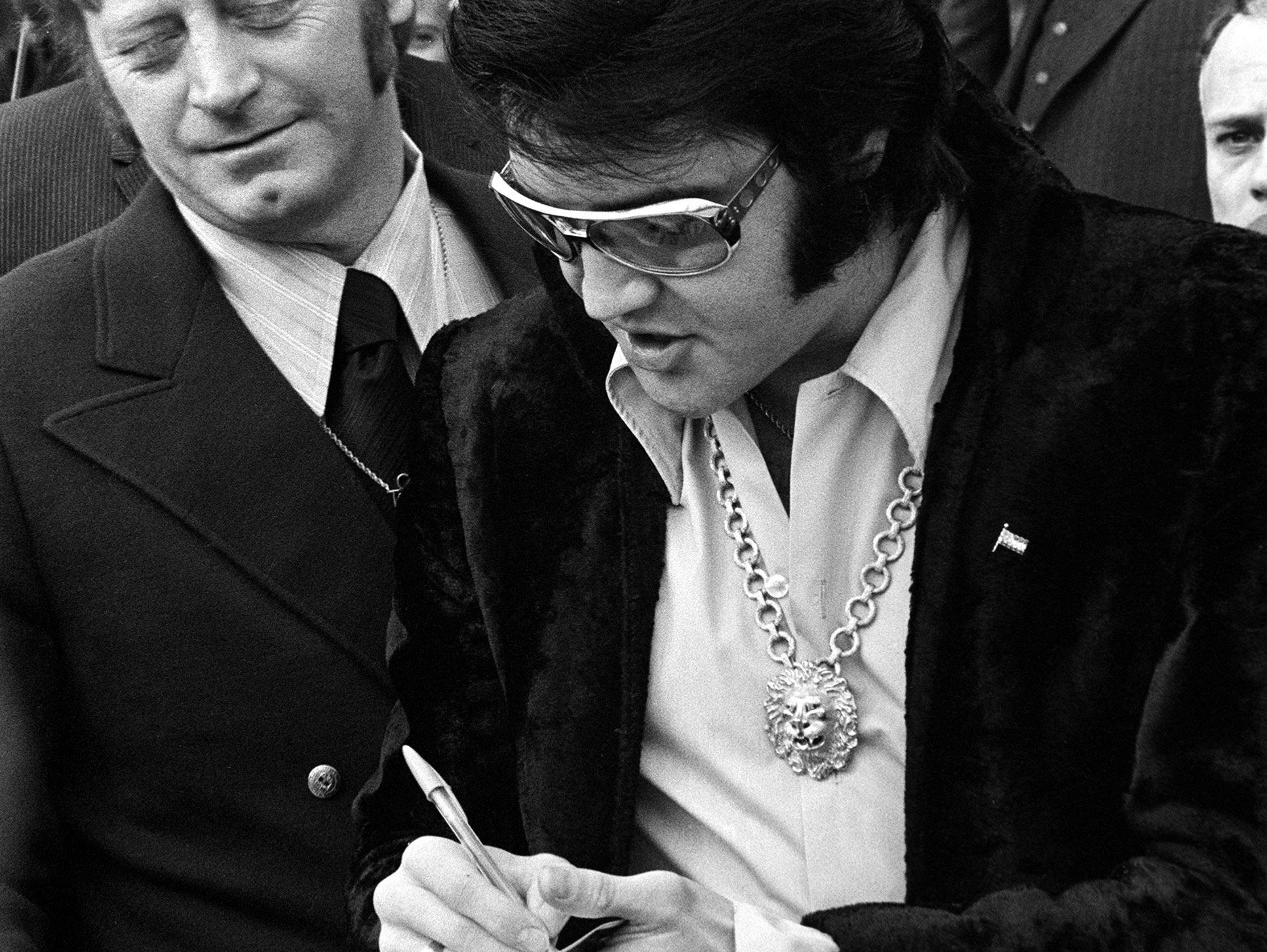    16 Jan 1971 - Photo by Dave Darnell.  Elvis Presley (cq) signs autographs for fans after leaving a luncheon at the Holiday Inn Rivermont.  At left is Red West (cq).  Behind West is William N. Morris (cq), former sheriff of Shelby County.  Presley 