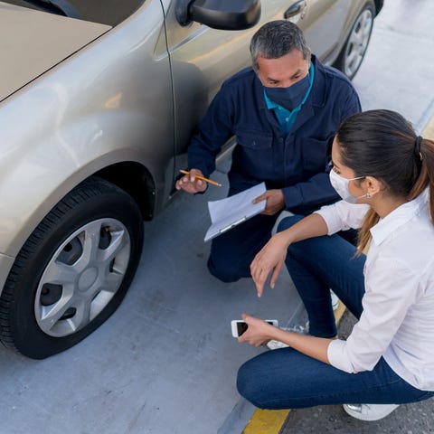 A mechanic reviews auto damage with a customer.