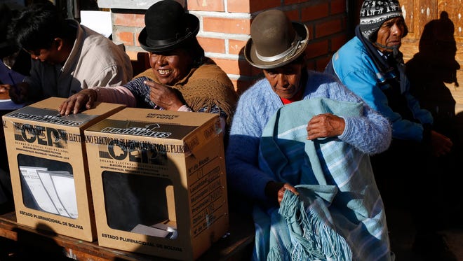 Poll workers stand behind ballot boxes during regional elections in Huarina, Bolivia, Sunday.
