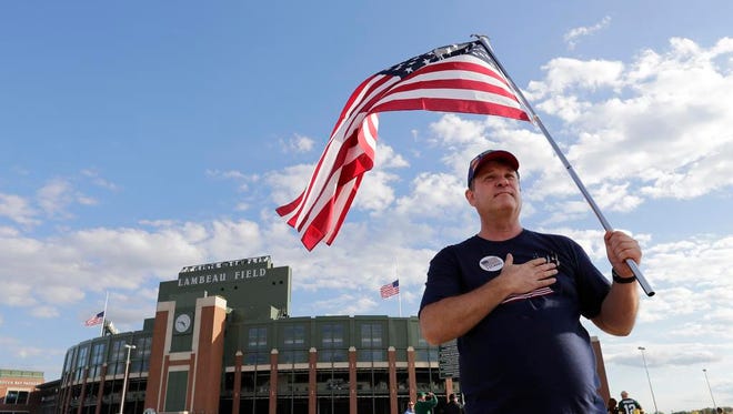 Green Bay Packers fan Tom of Appleton carries a flag and reminds people to have their hands over their hearts during the national anthem Thursday, Sept. 28, 2017, prior the the game against the Chicago Bears at Lambeau Field in Green Bay, Wis. "The flag isn't representing racism, the flag is representing freedom and the blood shed for that freedom. Kneeling is for prayer and sitting on the bench is for after you've played and you need a rest."