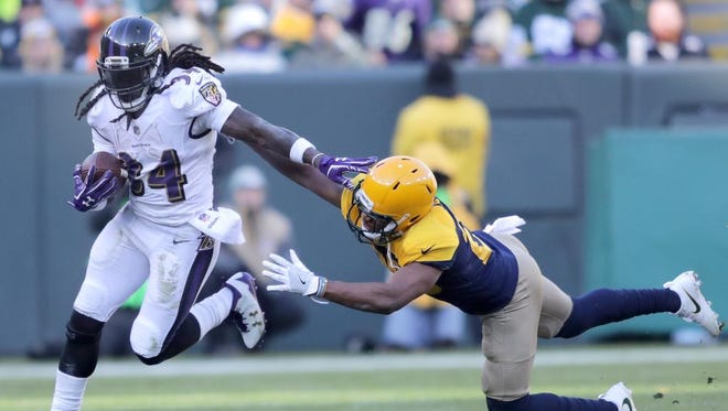 Baltimore Ravens running back Alex Collins stiff arms a Green Bay Packers defender on Nov. 19, 2017, at Lambeau Field.