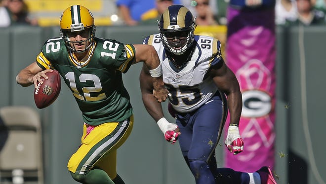 Green Bay Packers quarterback Aaron Rodgers (12) scrambles away from St. Louis Rams defensive end William Hayes on Sunday at Lambeau Field.