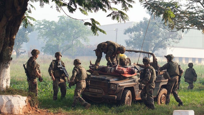 French soldiers lay a wounded man, who had been attacked during a protest, atop a military vehicle as they take him to get medical help, at Mpoko Airport in Bangui, Central African Republic, Monday, Dec. 23, 2013. Hundreds of demonstrators gathered at the entrance to the airport Monday morning carrying signs protesting Chadian forces and expressing support for French troops and other regional African forces. (AP Photo/Rebecca Blackwell)