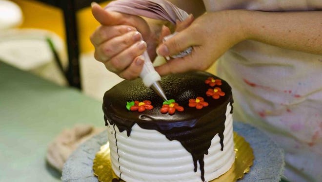 Final decorations are placed on a chocolate frosted cake in the early morning hours at Bing's In Newark.