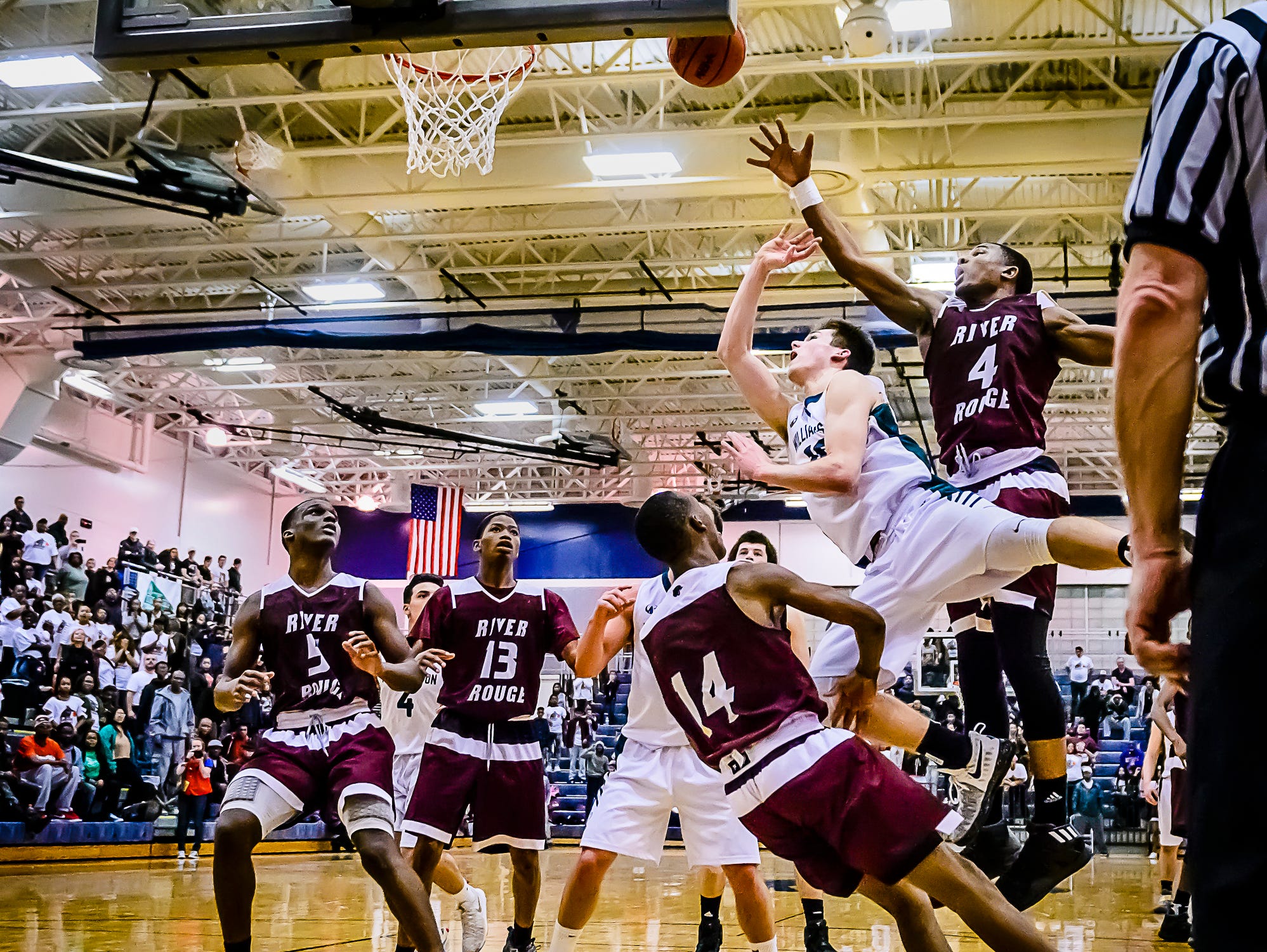 Mitchell Cook ,second from right, of Williamston lays the ball up and in as he collides with Jayvien Torrence ,14, of River Rouge with 18 seconds remaining in their Class B state quarterfinal game and the score tied at 51 Tuesday March 21, 2017 at Chelsea High School in Chelsea. The basket was waived off as Cook was charged with a player control foul.