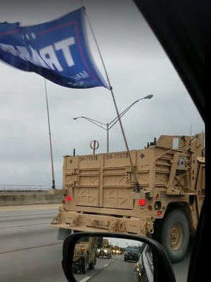 Truck in convoy of military vehicles flying a Trump flag