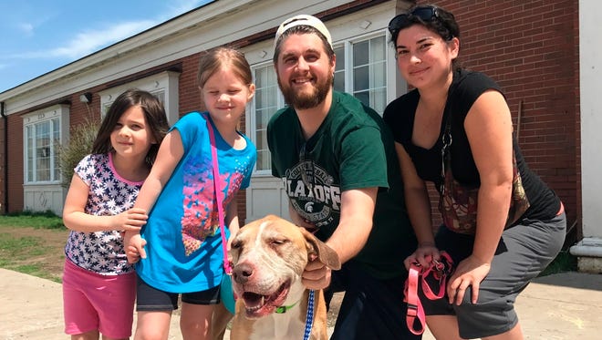 This May 5, 2018, photo provided by Laura Simmons-Wark, shows the Wieferich family holding their dog “Bambi” at the Lucas County Canine Care & Control in Toledo, Ohio.  The dog ran away from the Lansing, Mich., family four years ago was reunited with them after being found more than 100 miles away in Ohio and identified through a microchip. Bradley Wieferich said he was surprised by the call from a microchip company telling him Bambi had been found.