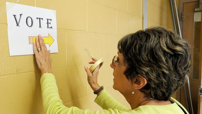 Gail White posts a sign indicating where to vote at North Side High School in Jackson on Monday.