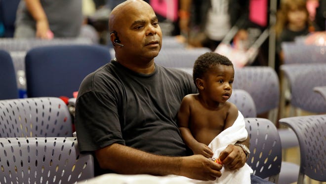 Evacuee Will Sutton, left, holds his 11-month son Jayden at the Lakewood Church in Houston, Texas, Tuesday, Aug. 29, 2017. Joel Olsten and his congregation have set up their church as a shelter for evacuees from the flooding by Tropical Storm Harvey. (AP Photo/LM Otero)