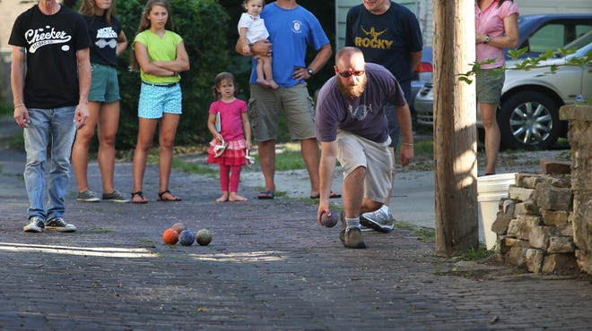 Meridian-Kessler resident Barry Pachciarz (center) and his family watch bocce being played in the alley behind their home in 
the 4300 block of Park Avenue. Among the players are Will Lonnemann (throwing ball) and Gregg Labita (far left).