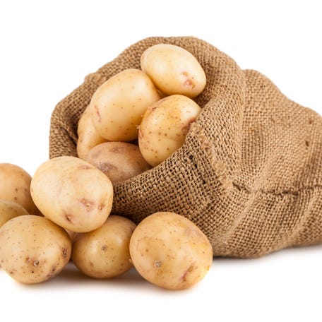 A sack of potatoes with potatoes sitting next to it