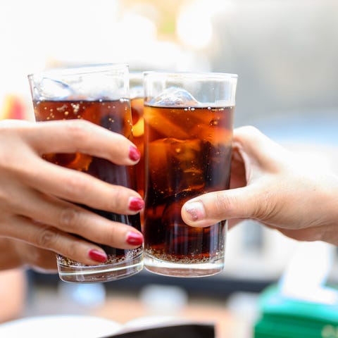 A group of people clinking their glasses of soda.