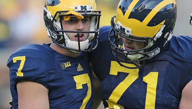 Michigan QB Shane Morris is helped off the field by offensive lineman Ben Braden during Saturday's loss to Minnesota.