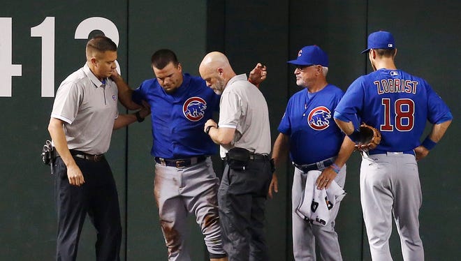 An injured Chicago Cubs' Kyle Schwarber, second from left, is attended to by training staff as manager Joe Maddon, second from right, and Ben Zobrist (18) look on during the second inning of a baseball game against the Arizona Diamondbacks Thursday, April 7, 2016, in Phoenix.