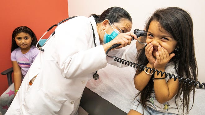 Emilie Sanchez, 4, giggles as Dr. Tess Ribay tickles her ears while checking her ear canal during an exam on Thursday at the Heart of Florida Health Center's new location. Emilie's older sister, Lezlie, 9, waits her turn. The center's new headquarters is located in the former Albertsons grocery store building on East Silver Springs Boulevard in Ocala.
