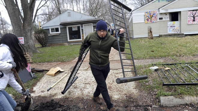 Volunteer Luis Cuenca helps students from the University of Michigan with cleanup efforts along Grayfield in Detroit. Community groups often use their own funds to cut grass, remove blight and board up run-down properties.