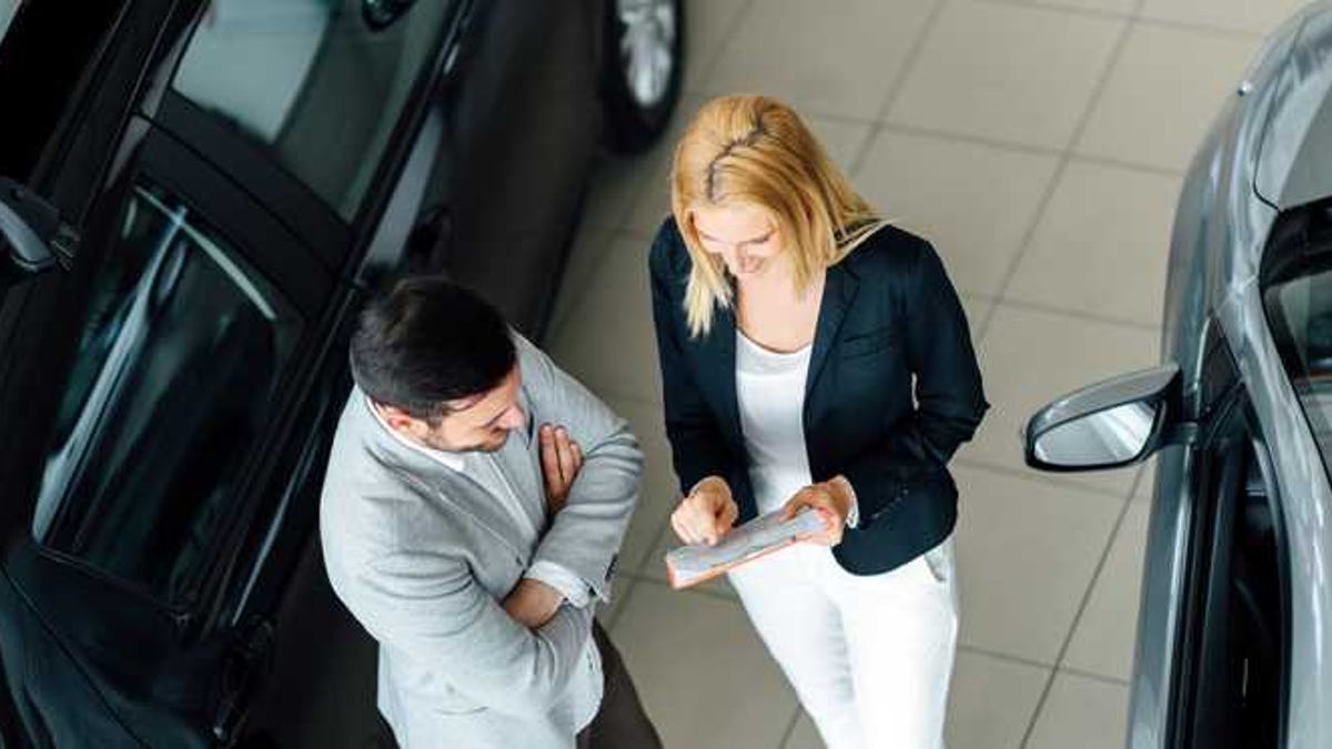 A man and a woman negotiate at a car dealer