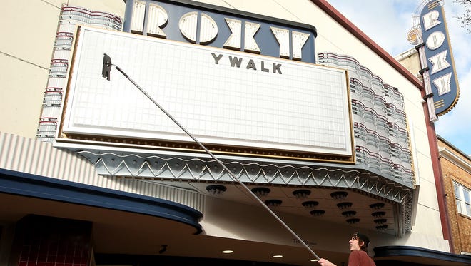 Tyler Stitt places letters on the marquee of the Roxy Theatre on Fourth Street in downtown Bremerton on Thursday. The theater reopens Friday.