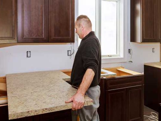 Man installing a new counter top in a kitchen.
