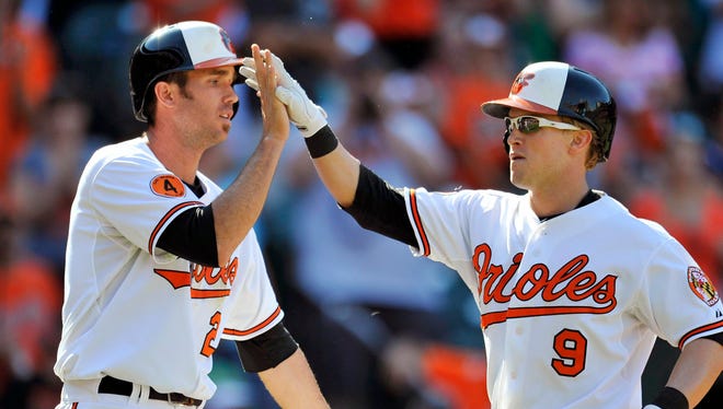 The Orioles’ Nate McLouth, right, is congratulated by J.J. Hardy after hitting a two-run homer against the Athletics on Sunday. Baltimore won 11-3 and remains very much alive in the AL playoff hunt.