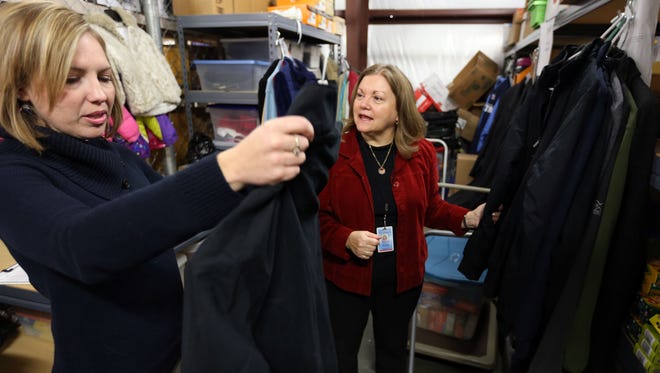 Eileen Woodside, a social worker with Rutherford County Schools, left, picks up a winter coat in 2014 for a student from Kim Snell, coordinator of the county school system’s ATLAS program, which works to assist homeless students.