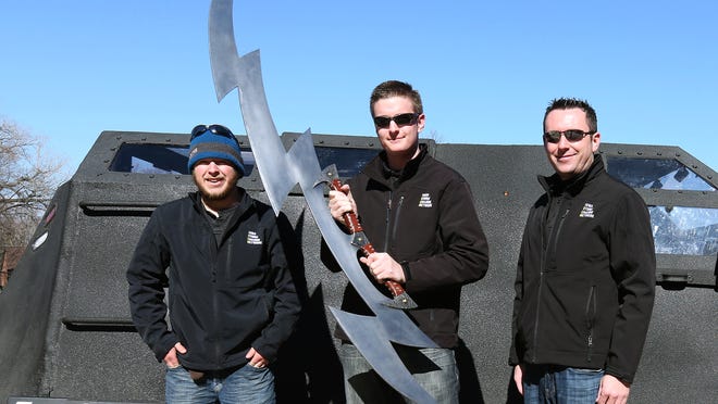 Zach Sharpe, a weather chaser from Norwalk, holds a large lightning-shaped sword alongside fellow chasers Brennan Jontz, left, of Bondurant, and Ben McMillan, right, of Scottsdale, Arizona, after speaking to students at Stowe Elementary School in Des Moines.