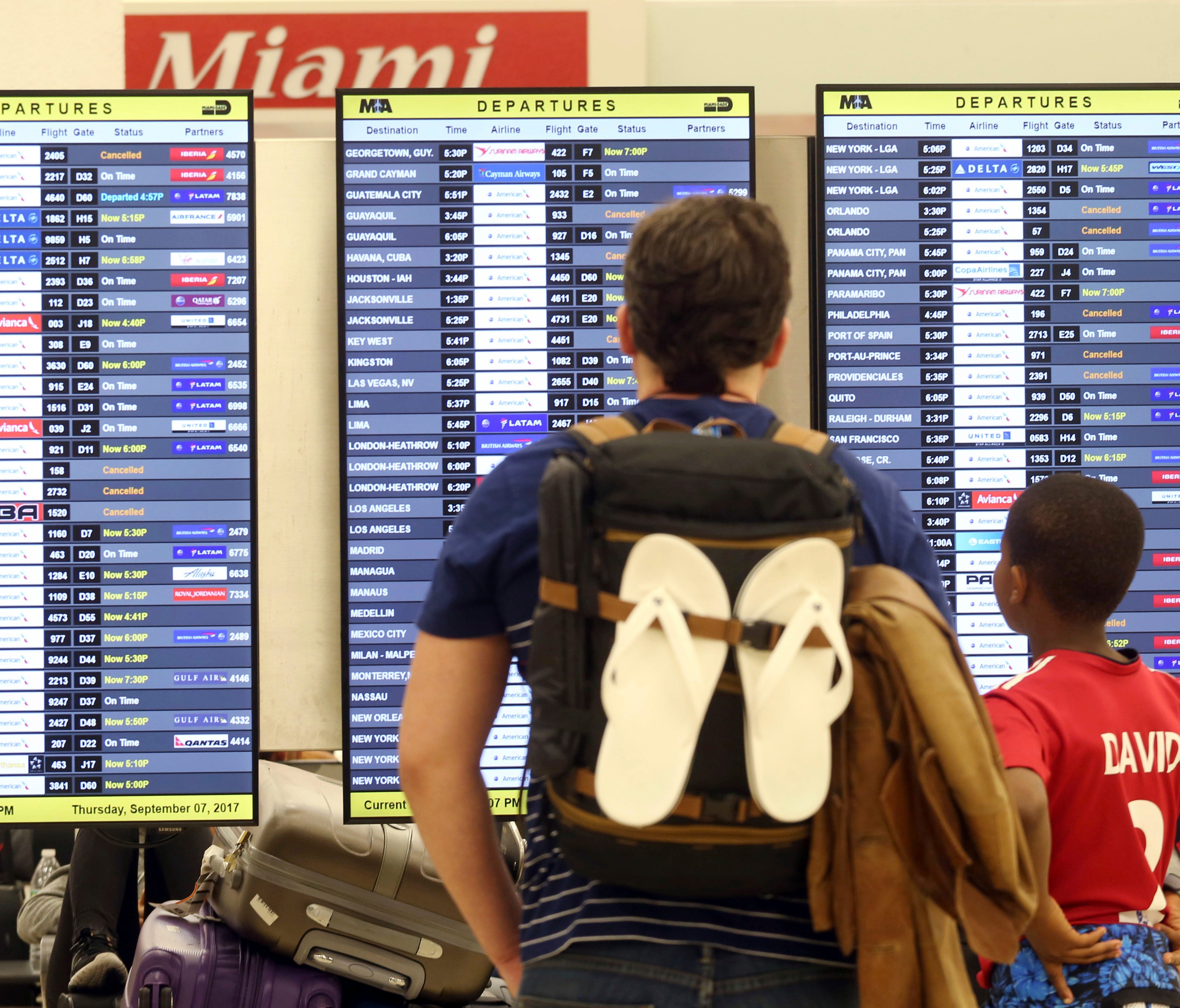 Passengers check the departure board at Miami International Airport on Thursday, Sept. 7, 2017.