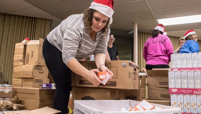 Brianna Pliley helps assemble food baskets for Santa's Helper at First United Methodist Church on Tuesday.