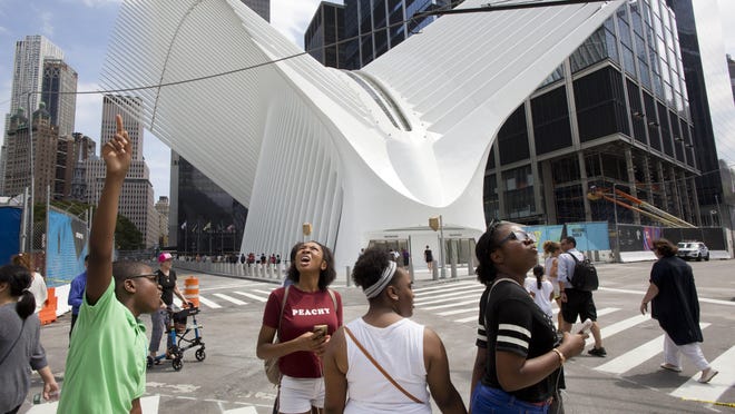 Visitors take in the sights at the World Trade Center in New York. Behind them is the newly opened transportation hub.