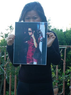 Thuan Le Elston holding a photo of Kim, the character she played in the movie "Heaven and Earth."
