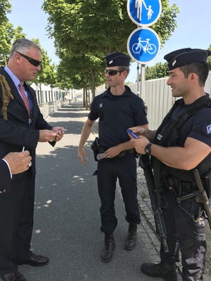Greg Donovan, executive director of the Orlando Melbourne International Airport, hands out patches worn by the airport's police officers to two French police officers at this week's Paris Air Show.